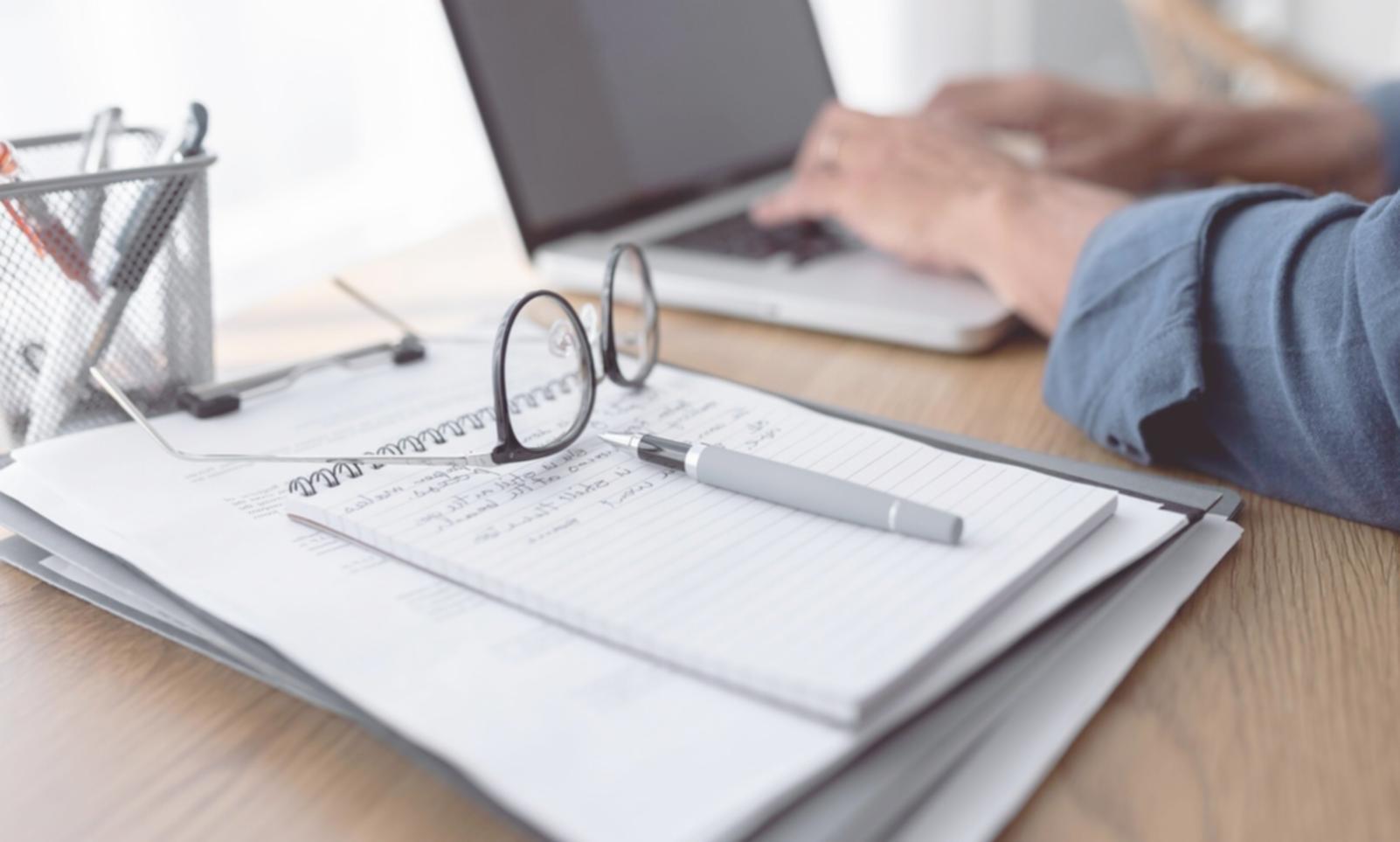 Persona revisando presupuestos estacionales con documentos y calculadora sobre mesa de madera